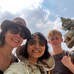 Guide Ning with Clare B. smiling during a Bangkok city tour, with urban scenery and cultural landmarks in the background.