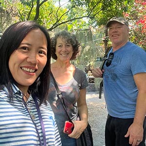 Guide Kanny with Erica O. in a Bangkok park, smiling amid greenery with trees, walking paths, and open sky in the background. 