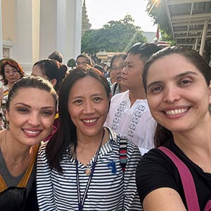 Guide Kanny with Kathleen B. at Wat Pho in Bangkok, smiling with temple structures and ornate architecture in the background. 