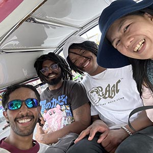 Guide Kung with Khephren A. beside a vibrant tuk-tuk in Bangkok, smiling with city streets and local traffic in the background. 