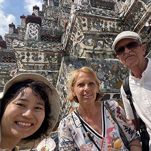 Guide Ning with Reinhold U. at Wat Arun in Bangkok, smiling with the temple’s mosaic-covered spires rising in the background. 