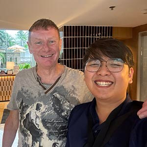 Guide Time with Shane P. at a hotel meetup in Bangkok, smiling in a modern lobby with polished decor and ambient lighting.