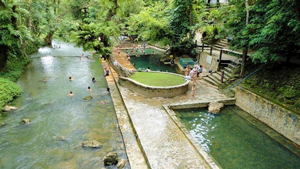 Tourists enjoying Hin Dad Hot Springs in Kanchanaburi, Thailand – relaxing thermal pools beside a forest stream