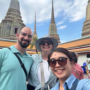 Guide Gwen with Jane K. at Wat Arun, smiling with the temple’s ornate spires and mosaic-decorated towers behind them.