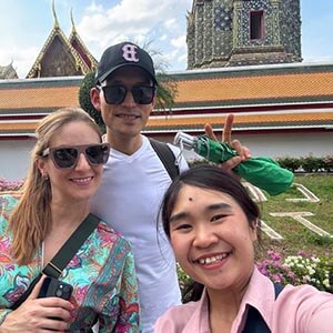 Guide Gwen with Juan R. at Bangkok’s Grand Palace, smiling with golden rooftops and ornate temple structures in the background. 